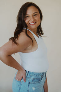 side view of model wearing the change your mind bodysuit in the color white. model has the bodysuit paired with the charleston denim.