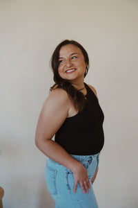 side view of model wearing the change your mind bodysuit in the color black. model has the bodysuit paired with the charleston denim.
