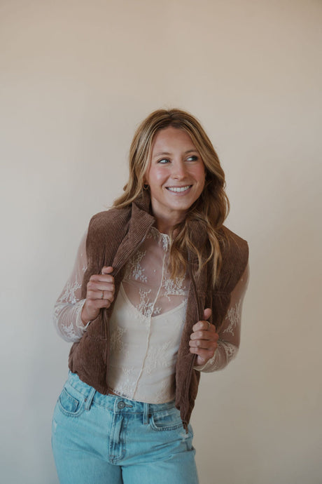 front view of model wearing the seems so simple puffer vest in the color cocoa. model has the vest paired with the here to stay top in the color cream and the charleston denim.