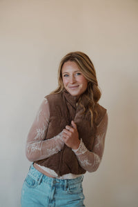 front view of model wearing the seems so simple puffer vest in the color cocoa. model has the vest paired with the here to stay top in the color cream and the charleston denim.