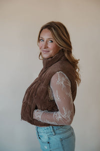 side view of model wearing the seems so simple puffer vest in the color cocoa. model has the vest paired with the here to stay top in the color cream and the charleston denim.