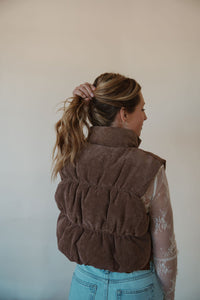 back view of model wearing the seems so simple puffer vest in the color cocoa. model has the vest paired with the here to stay top in the color cream and the charleston denim.