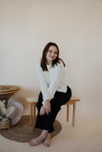 Load image into Gallery viewer, front view of model wearing the Addison denim in the color fade black. model has the denim paired with the somewhere in the middle sweater in the color white.