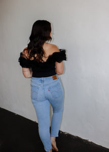 model wearing the crazy in love bodysuit in the color black. model has the top paired with a pair of light wash denim.