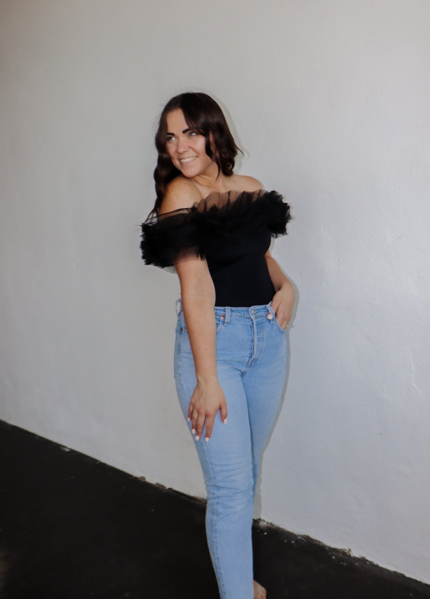 model wearing the crazy in love bodysuit in the color black. model has the top paired with a pair of light wash denim.