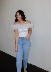 model wearing the crazy in love bodysuit in the color white. model has the top paired with a pair of light wash denim.