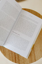 Load image into Gallery viewer, inside page photo of &quot;the secure soul: an identity anchored in the love of Christ&quot; devotional book by Tammy L Smith. book is shown sitting on a stool.