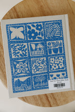 Load image into Gallery viewer, back cover photo of &quot;God our Home&quot; by Katie Noble. book is shown sitting on a wooden stool.