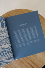 Load image into Gallery viewer, inside page photo of &quot;God our Home&quot; by Katie Noble. book is shown sitting on a wooden stool.