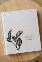 Load image into Gallery viewer, cover photo of &quot;songs for the suffering&quot; by Julia Allspaw. book is shown sitting on a wooden stool.