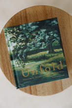 Load image into Gallery viewer, cover photo of &quot;unfold: discovering the thoughts and intentions of the heart&quot; devotional book by Lisel Lamprecht. book is shown sitting on a stool.