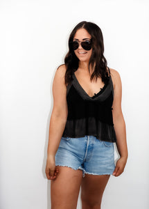 model wearing the moving on top in the color black paired with light denim shorts; model is wearing a pair of sunglasses