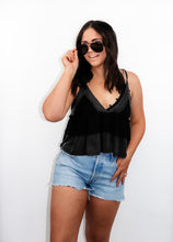 Load image into Gallery viewer, model wearing the moving on top in the color black paired with light denim shorts; model is wearing a pair of sunglasses and has one hand pinching the frames