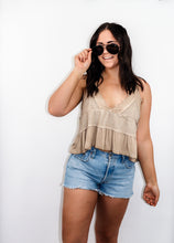 Load image into Gallery viewer, model wearing the moving on top in the color taupe paired with light denim shorts; model is wearing a pair of sunglasses with one hand pinching the frames