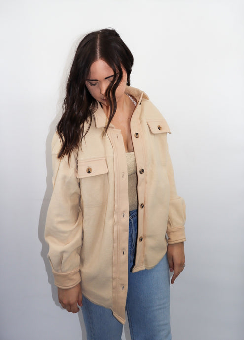model wearing the until then jacket. model has the jacket paired with a pair of denim and is looking downward.