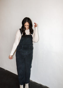 model wearing the sweet disposition overalls in the color charcoal. model has the overalls paired with the by your side top in the color cream.