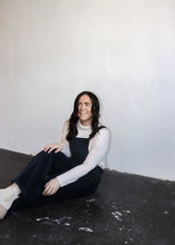 Load image into Gallery viewer, model wearing the sweet disposition overalls in the color charcoal. model has the overalls paired with the by your side top in the color cream.