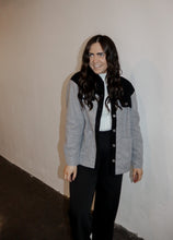 Load image into Gallery viewer, model wearing the never say never jacket in the color black/charcoal. model has the jacket paired with the all along sweater vest and the logan trousers in the color black.